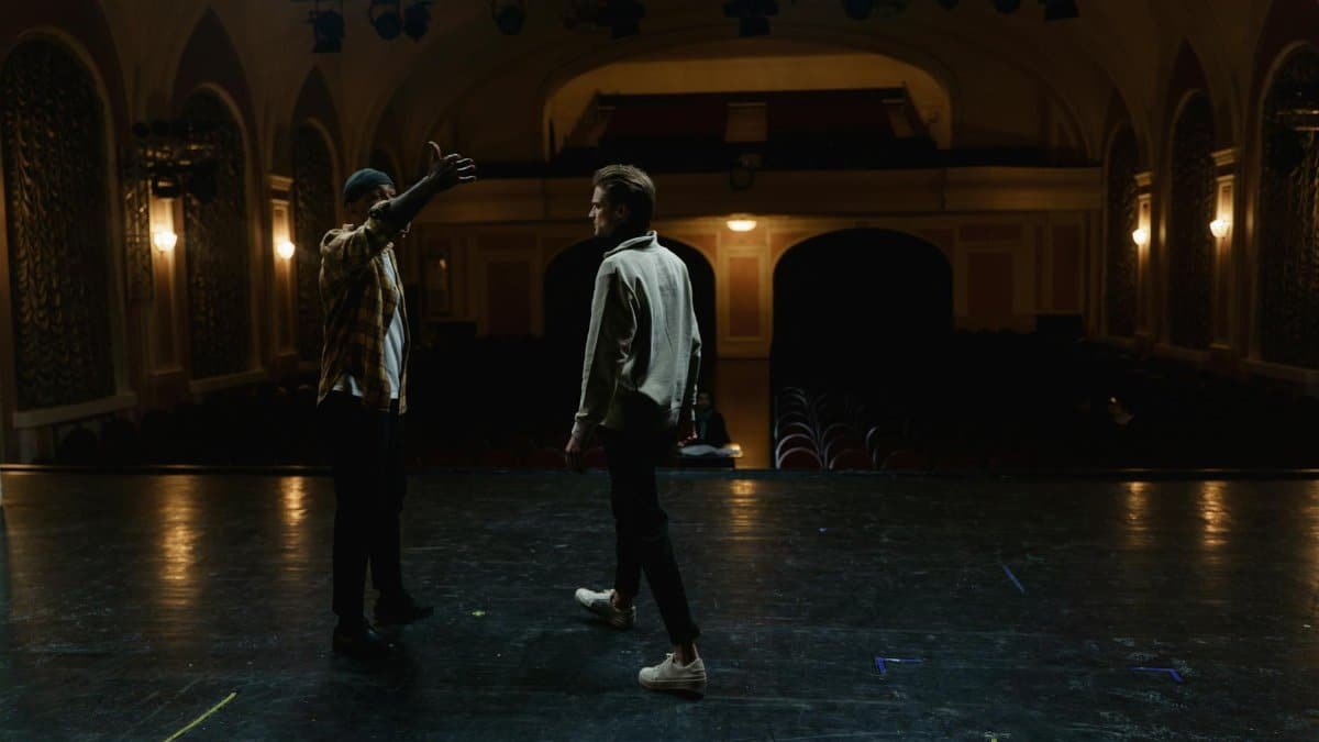 Two men on stage practicing a scene in an empty theater, demonstrating drama and performance art.