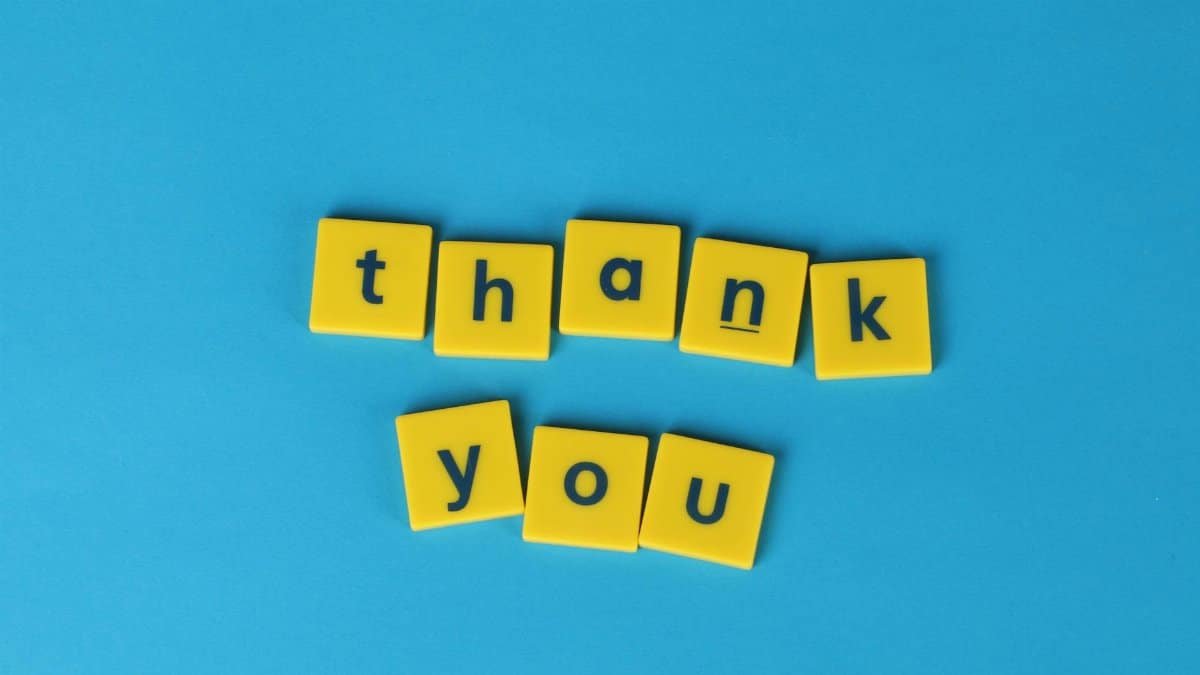 Bright yellow letter tiles spelling 'thank you' on a blue background, perfect for gratitude notes.