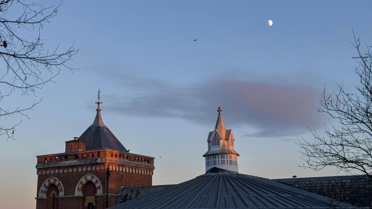 Evening view of historic Harrow architecture with moon and skyline.