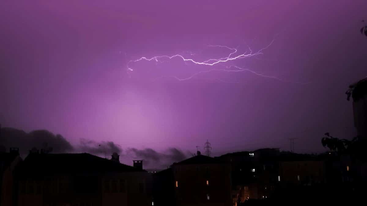 Stunning display of lightning illuminating the night sky over city buildings, capturing nature's dramatic ambiance.