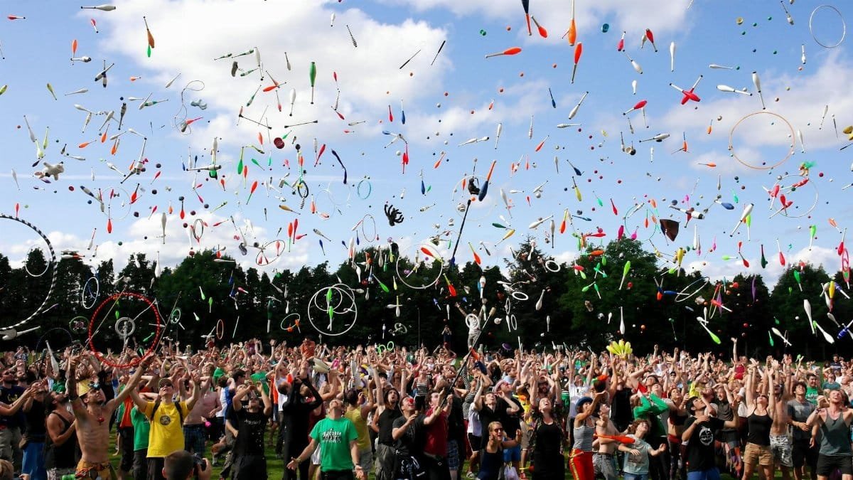 A lively crowd enjoying a colorful juggling event outdoors. Perfect for summer festival themes.