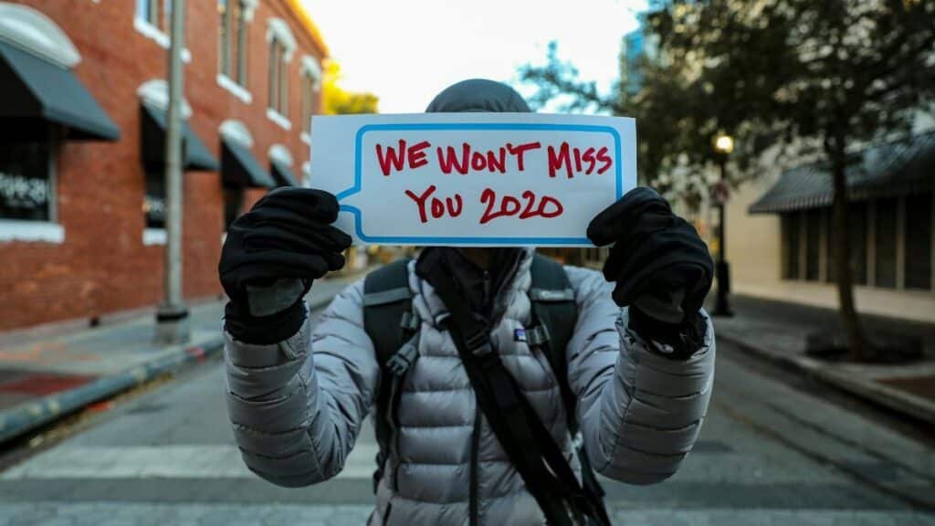 An individual in warm clothing holds a 'We Won't Miss You 2020' sign on a street in Orlando, Florida.