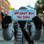 An individual in warm clothing holds a 'We Won't Miss You 2020' sign on a street in Orlando, Florida.