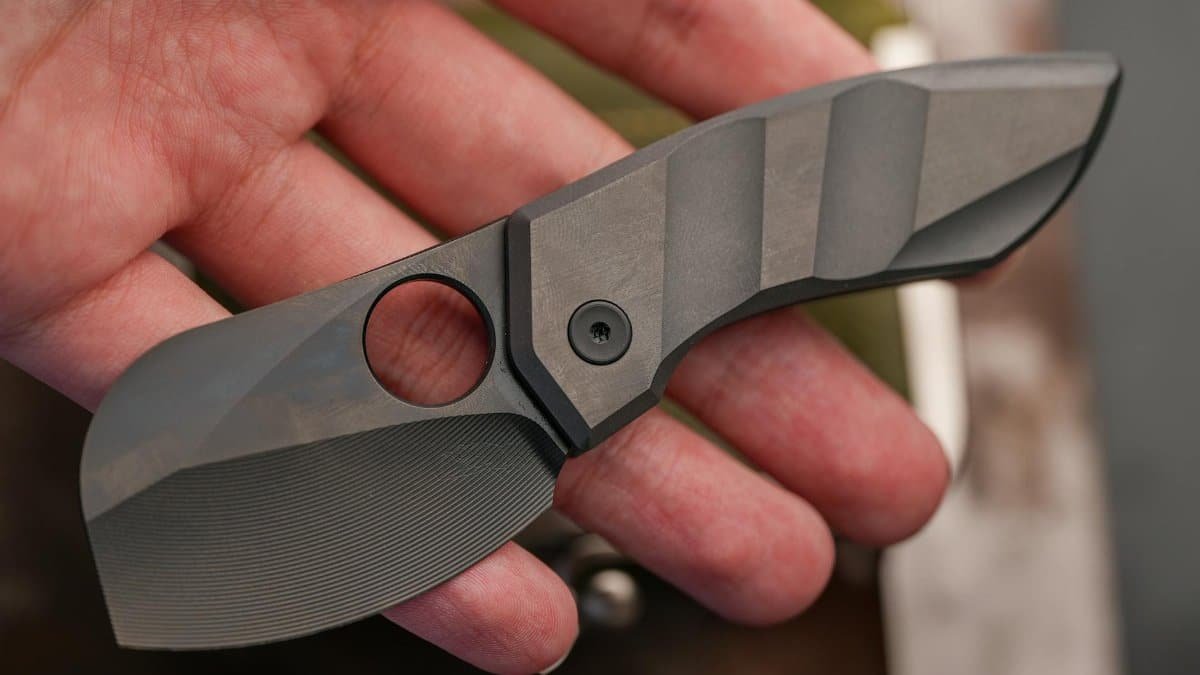 Close-up of a compact tactical folding knife held in a hand, showcasing sleek design and craftsmanship.