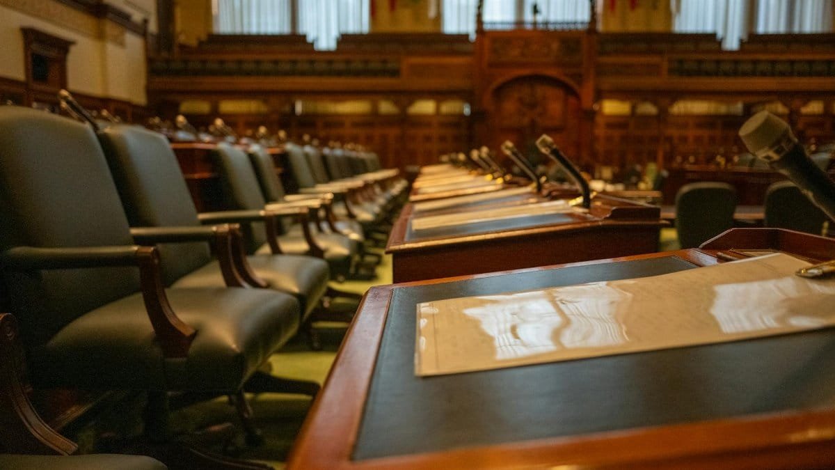 A detailed view of an empty legislative chamber with rows of desks and microphones, evoking governance.