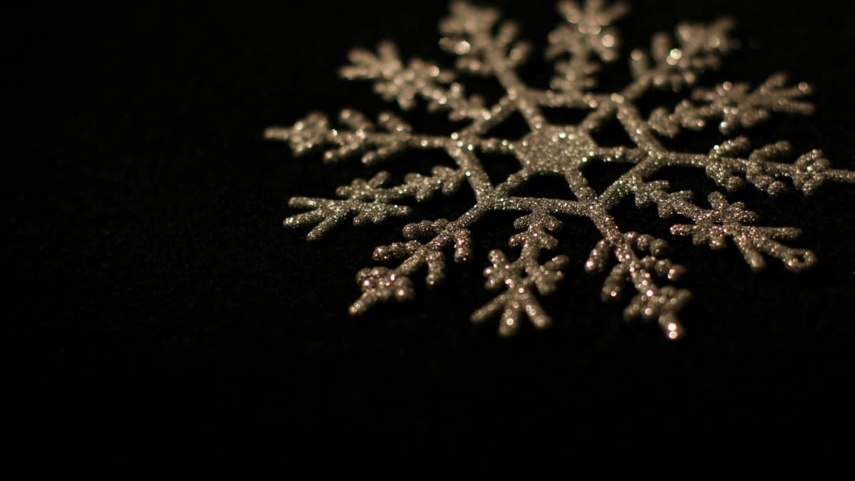 A close-up of a glittery decorative snowflake on a dark background, perfect for winter themes.
