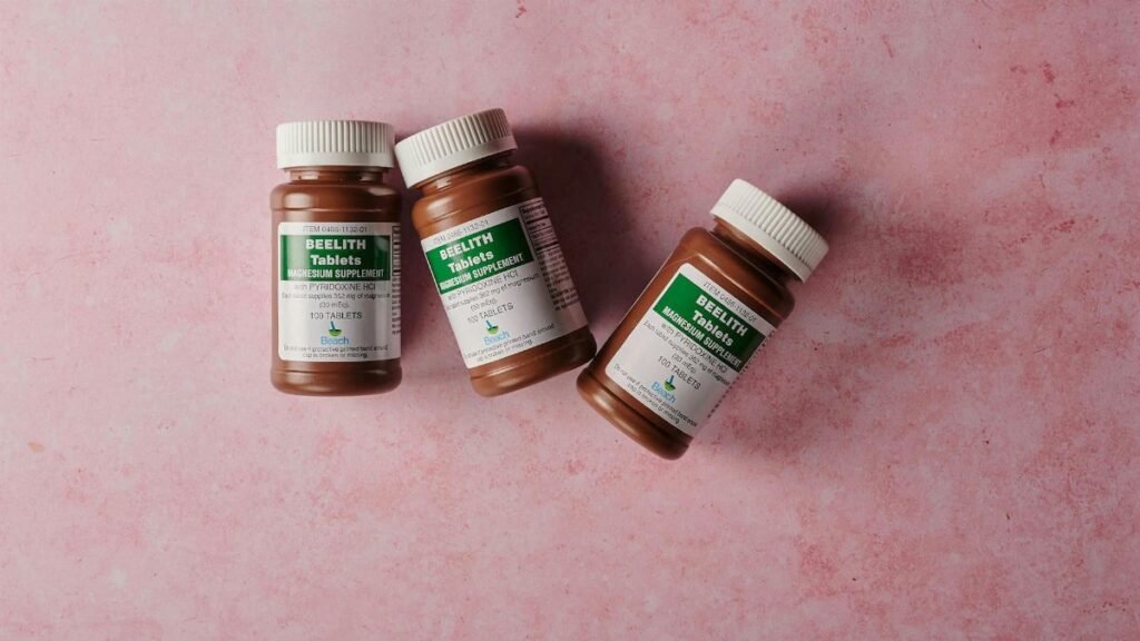 Three brown bottles of magnesium tablets on a soft pink background, ideal for health-themed content.