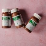 Three brown bottles of magnesium tablets on a soft pink background, ideal for health-themed content.