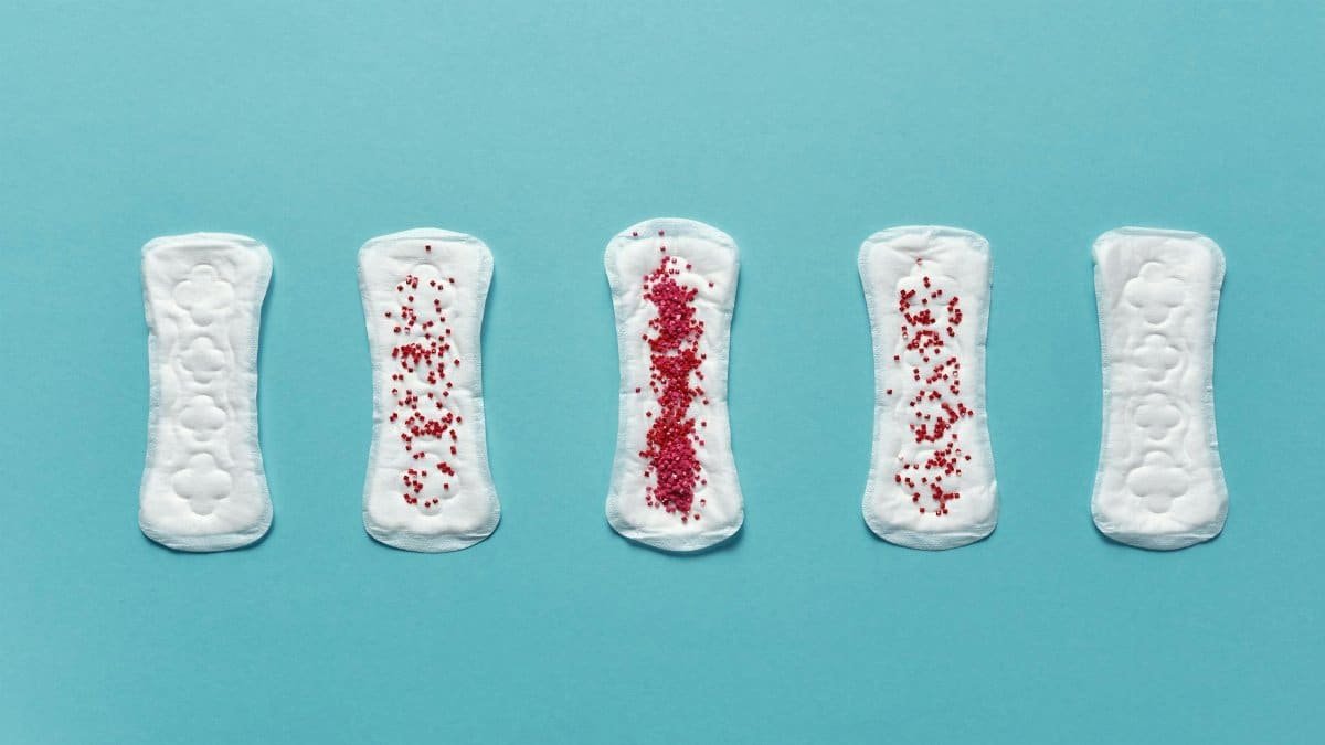 Various menstrual pads arranged on a blue background showcasing stages of use.