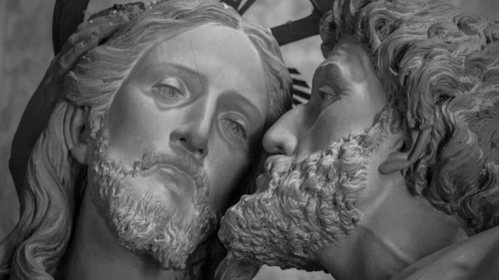 Close-up of a sculpture depicting the kiss of betrayal by Judas to Jesus in grayscale.