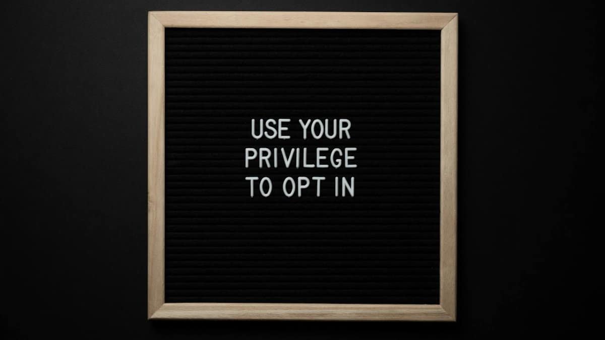 From above composition of contrast blackboard in wooden frame with white USE YOUR PRIVILEGE TO OPT IN title on black background