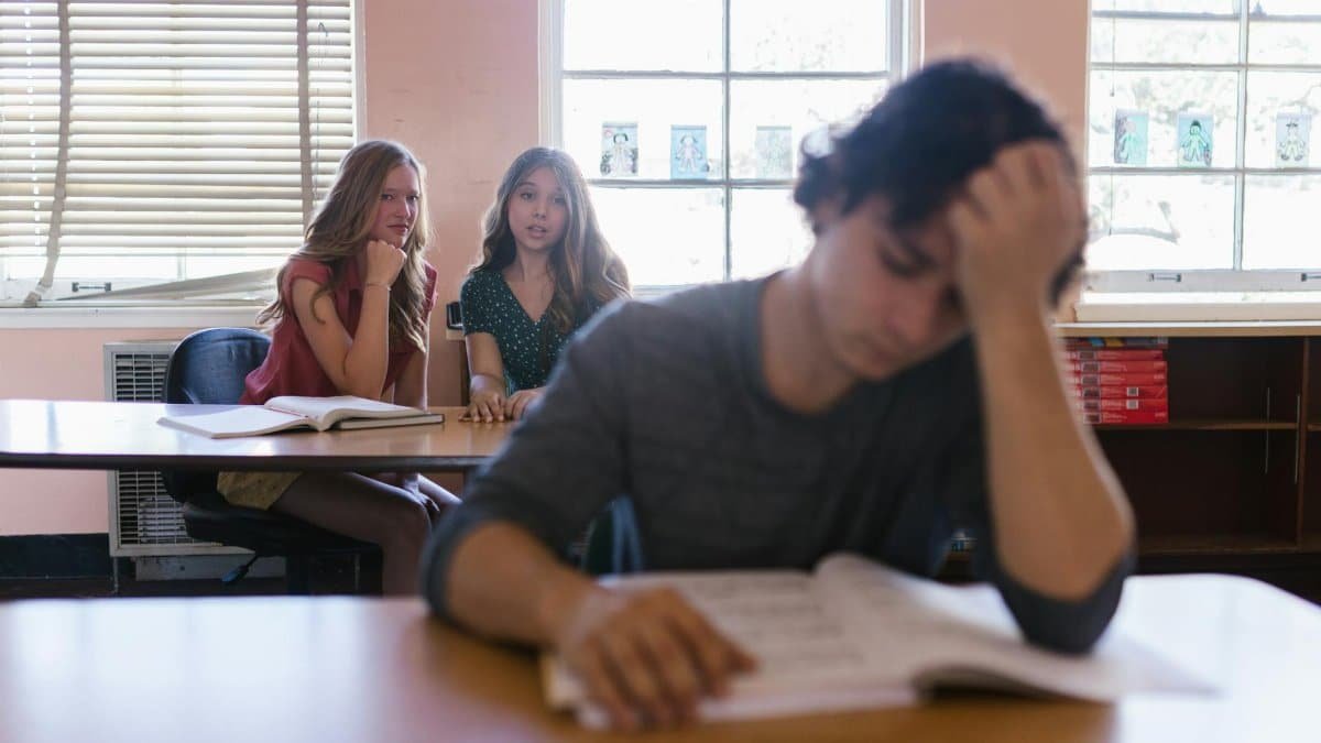 Focused on a teenager feeling bullied in a classroom environment with peers.