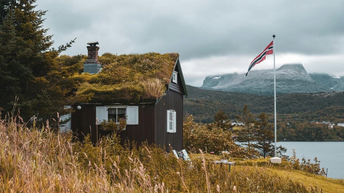 Norwegian cottage with grass roof by fjord and mountains in Saltstraumen, Norway.