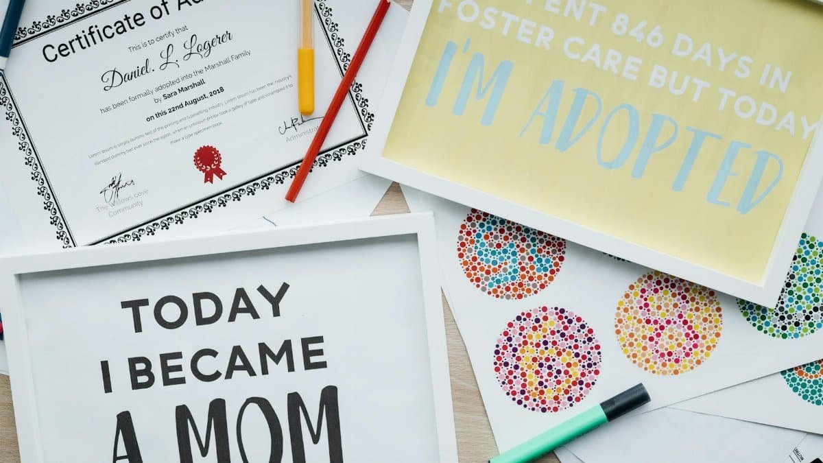 Heartfelt adoption announcement with colorful posters and official certificate on a desk.