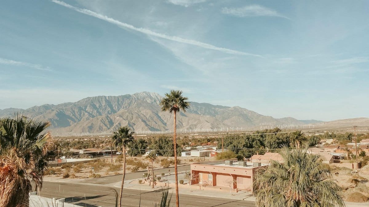 Stunning desert landscape in Palm Springs, CA, featuring mountains, palm trees, and clear skies.
