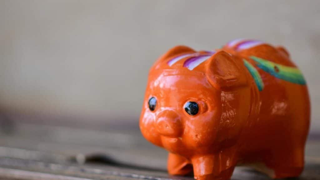 A close-up of a bright orange ceramic piggy bank with colorful patterns, symbolizing savings.