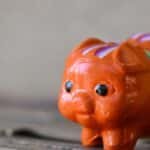 A close-up of a bright orange ceramic piggy bank with colorful patterns, symbolizing savings.