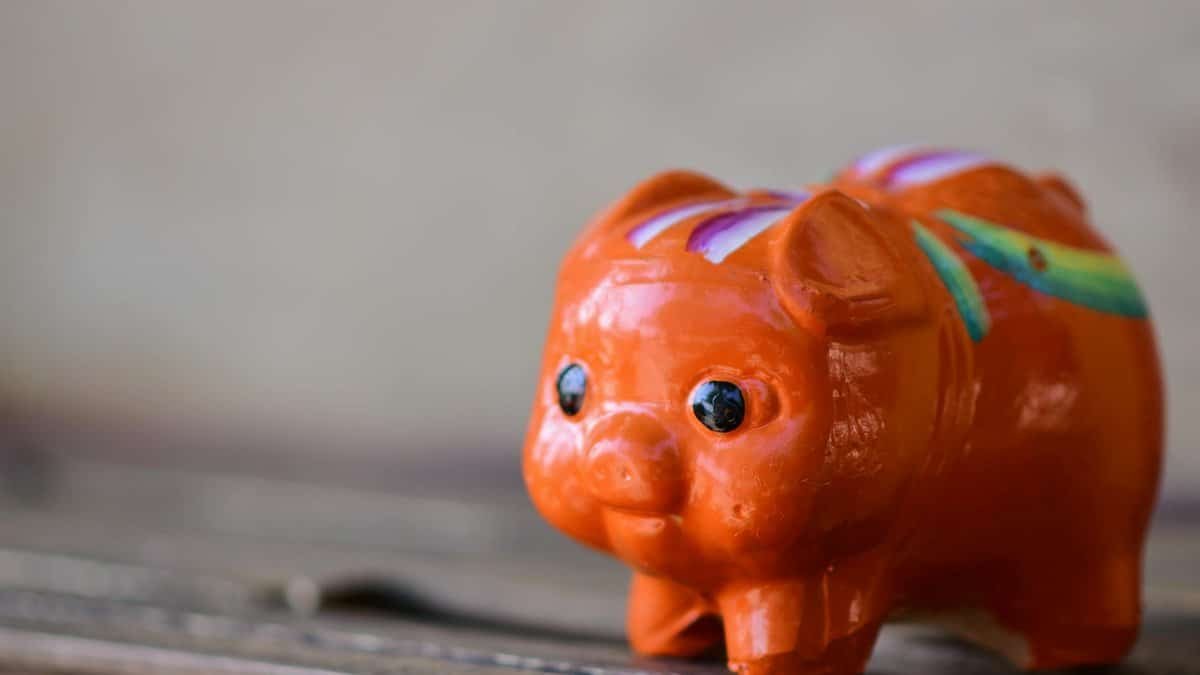 A close-up of a bright orange ceramic piggy bank with colorful patterns, symbolizing savings.