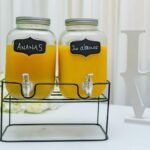 Elegant setup of pineapple and orange juice dispensers in glass jars, perfect for events.