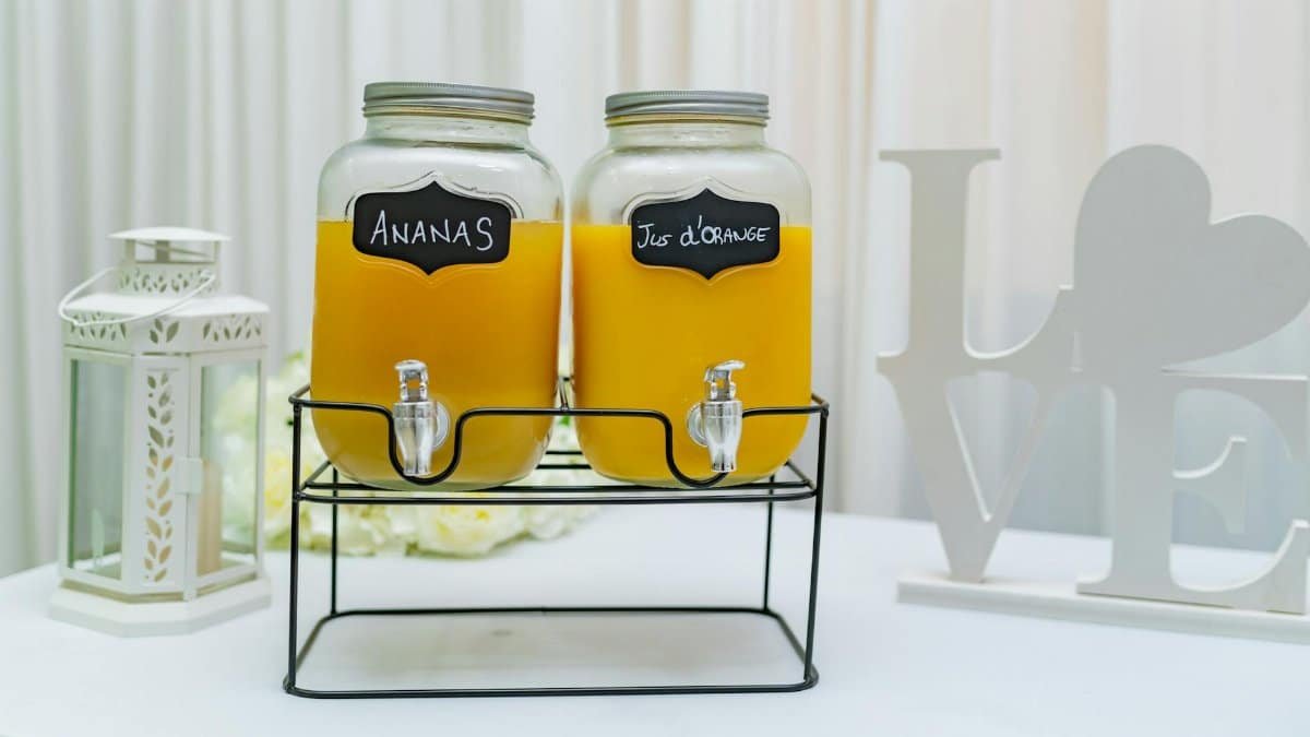 Elegant setup of pineapple and orange juice dispensers in glass jars, perfect for events.