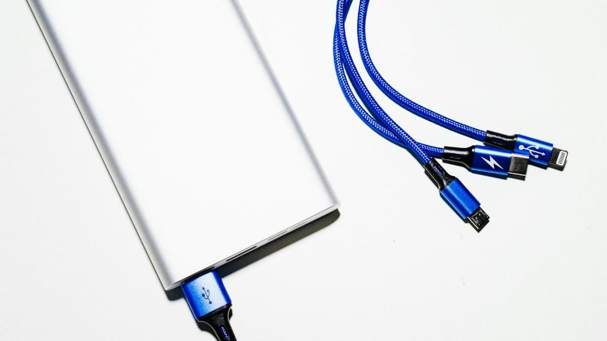 Minimalist image of a power bank with blue USB charging cables on a white background.