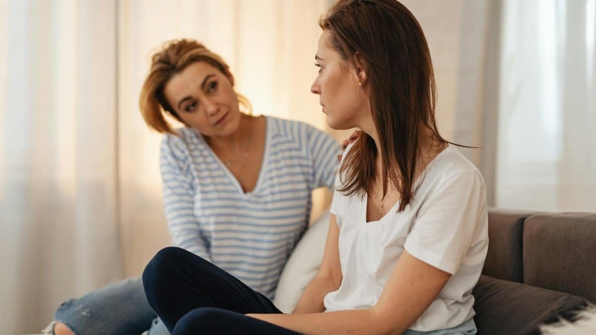 Two women having a heartfelt conversation on a couch, showing empathy and support.