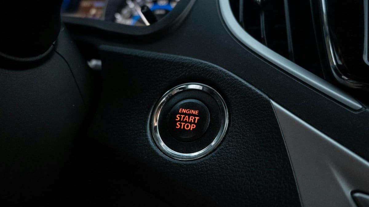Close-up image of a car's engine start stop button on the dashboard.