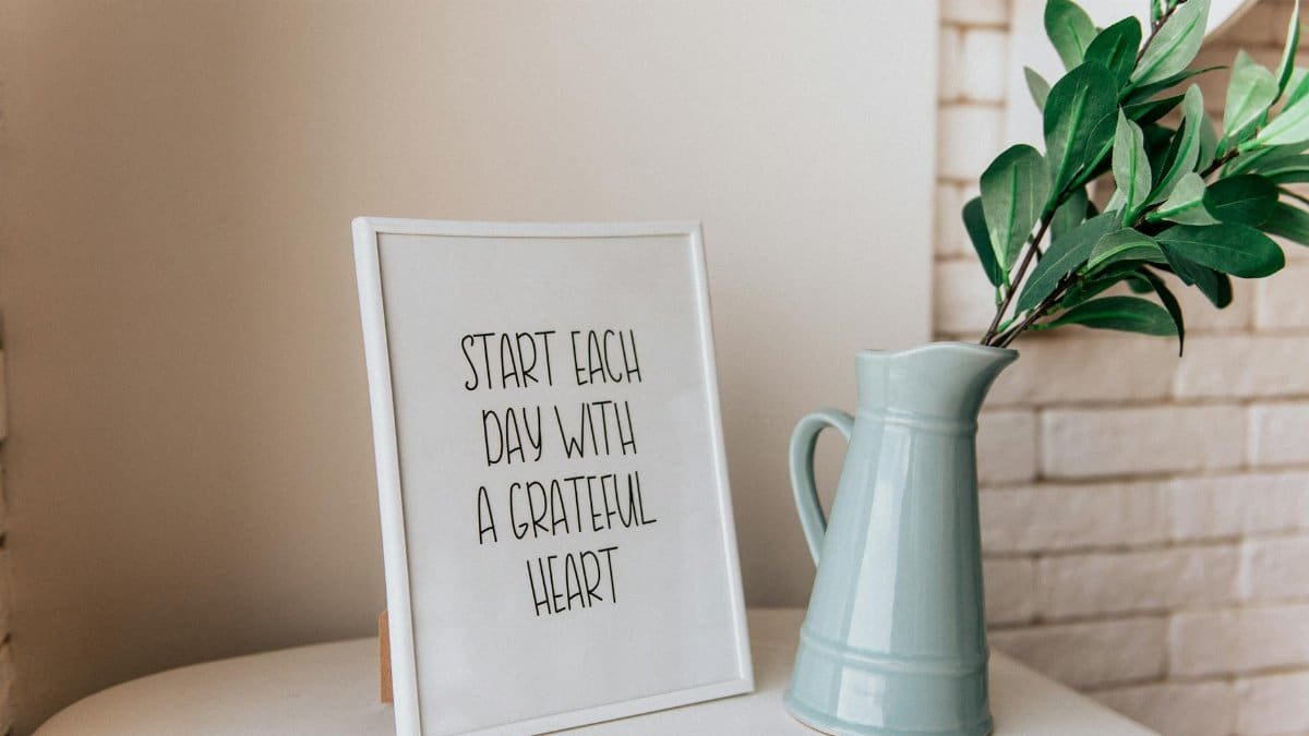 Framed quote 'Start each day with a grateful heart' next to a vase indoors.
