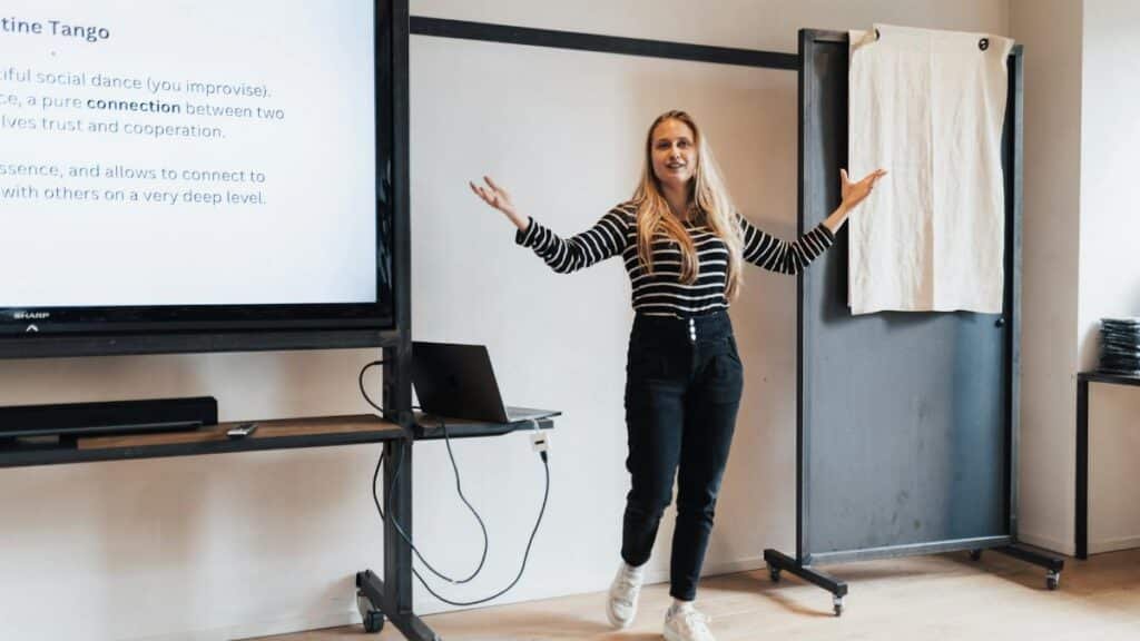 Businesswoman presenting a lecture in an office with a screen display and a laptop.