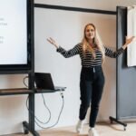 Businesswoman presenting a lecture in an office with a screen display and a laptop.