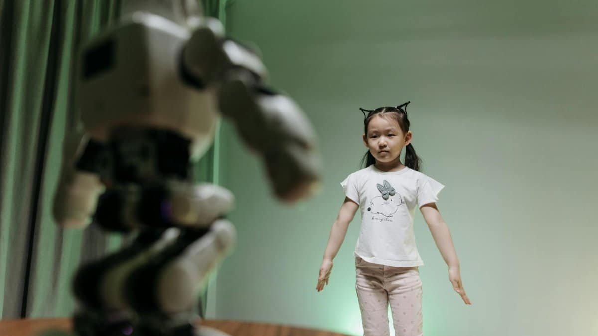 An Asian child interacts with a humanoid robot indoors, embracing innovation and play.