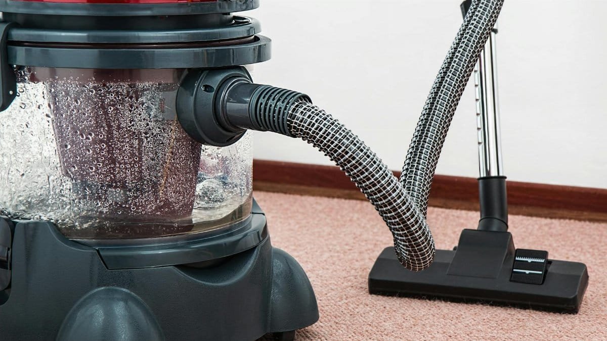 Close-up of a modern vacuum cleaner with water filtration on carpet floor indoors.