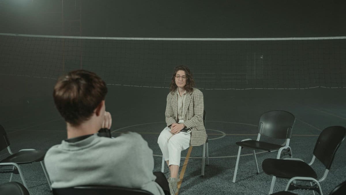 Two people engaged in a psychological support session in a gym setting, focused on mental health and therapy.