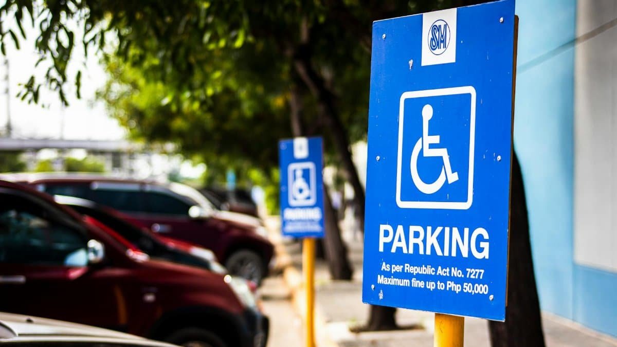 Signboard representing rule for disabled people parking only near vehicles and sidewalk in city