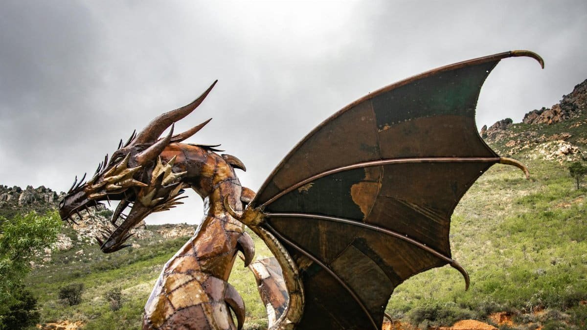 Impressive dragon sculpture set against rugged outdoor scenery with dramatic sky.