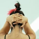 A woman performing yoga indoors, hands clasped behind head, stretching gracefully.