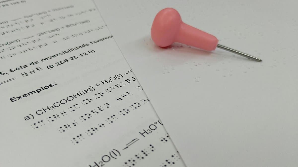 Braille chemistry sheet with pink pin for tactile learning.