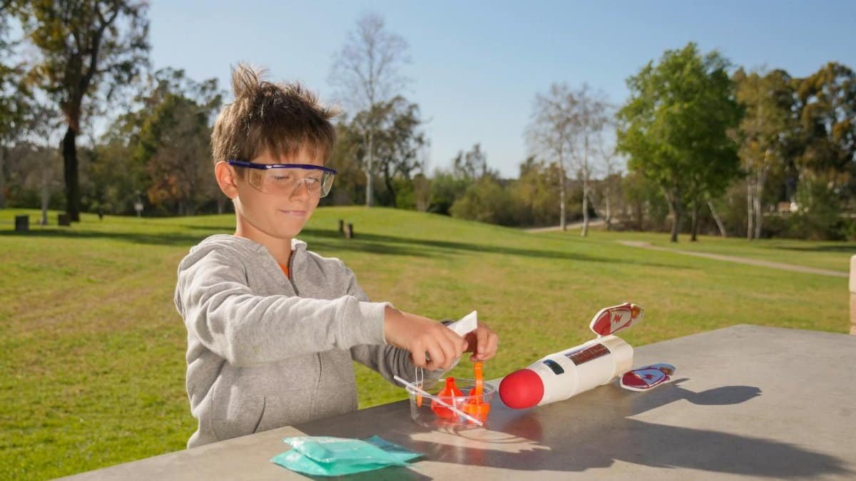 A child outdoors conducting a science experiment with a toy rocket.