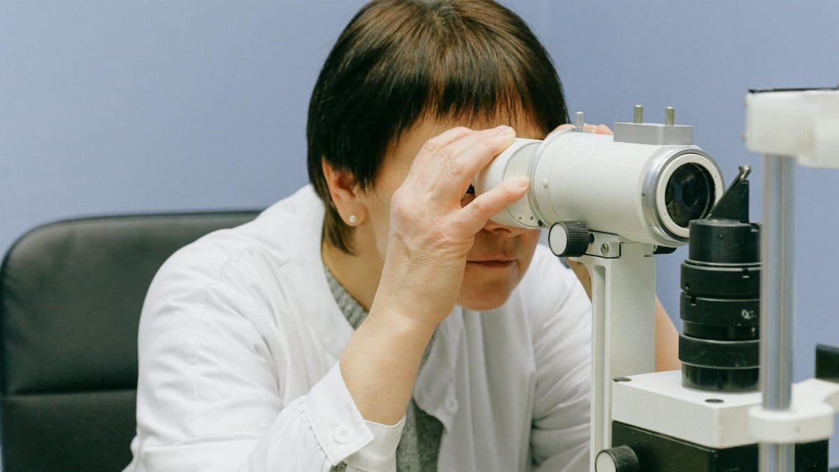 Woman focused on scientific research using a laboratory microscope indoors.