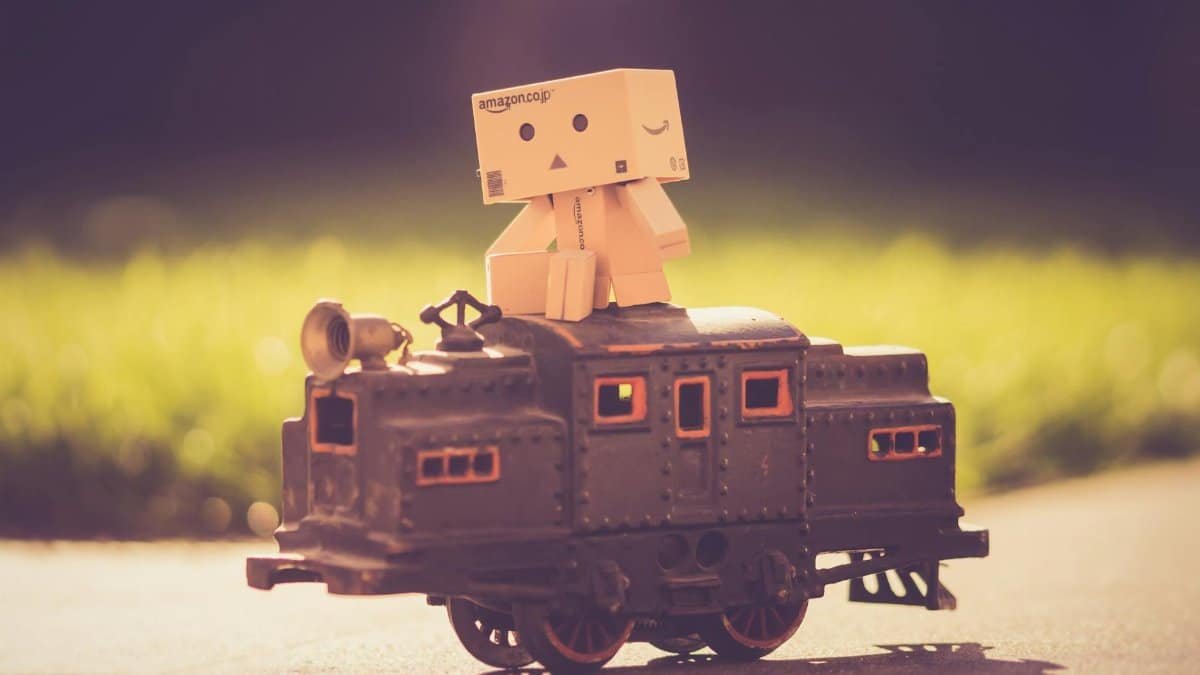 A whimsical miniature train with a Danbo figurine enjoying a sunny outdoor setting.
