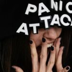 Close-up of a woman in a hoodie with 'panic attack' text, conveying anxiety.