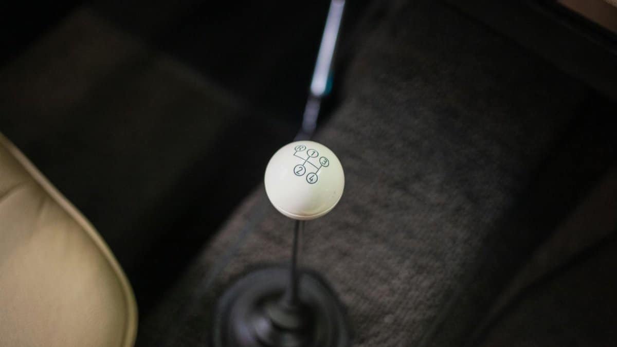 Close-up view of a vintage car's manual gear shift lever with a focus on the classic design.