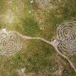 Two spiral stone labyrinths on a grassy field captured from above.