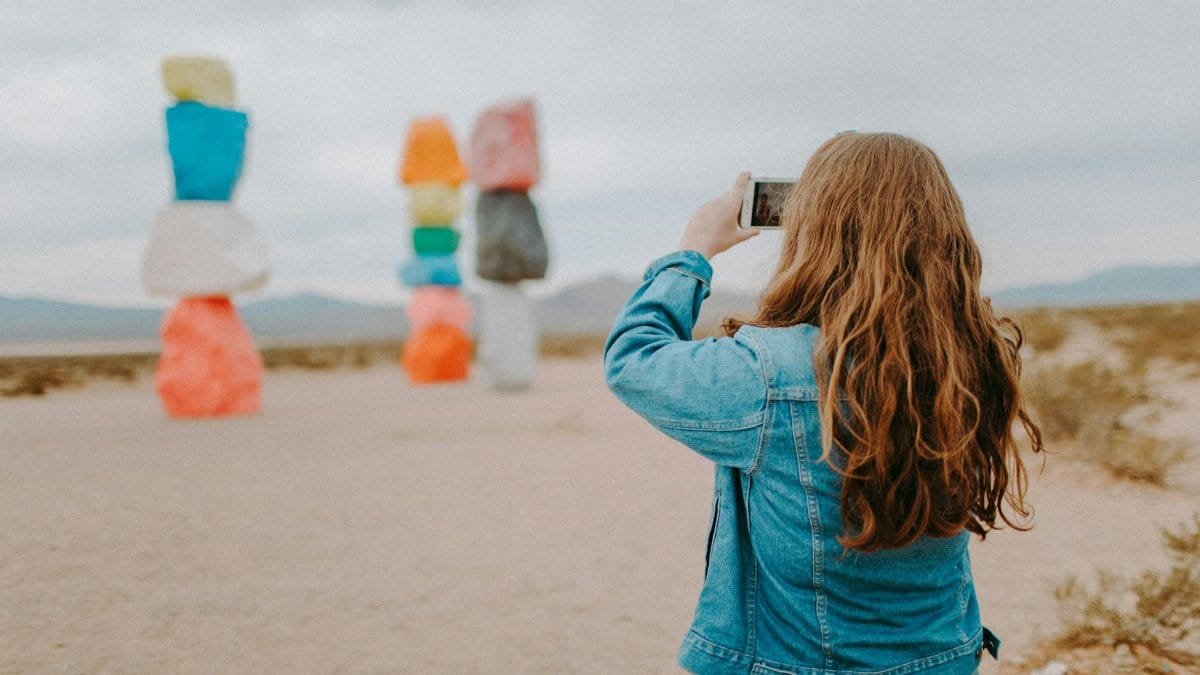 A tourist in denim captures the vibrant Seven Magic Mountains near Las Vegas, Nevada.