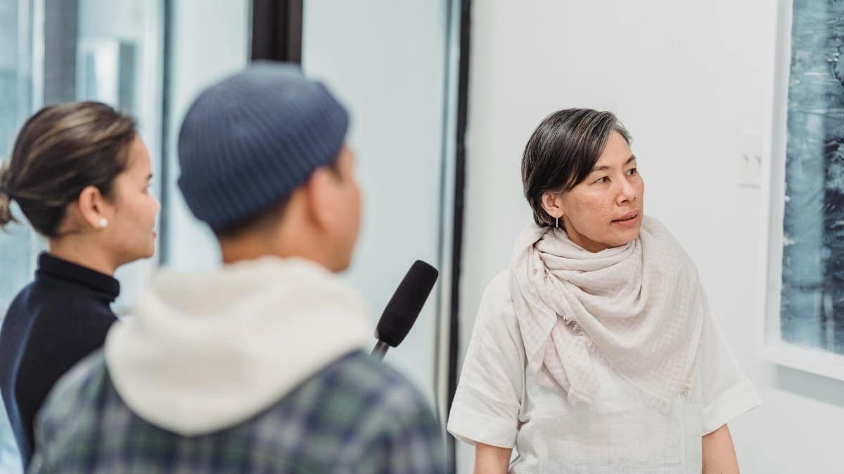 A casual interview with reporters in an indoor setting, featuring microphones and engaged discussion.