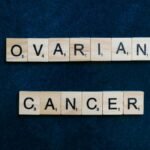 Scrabble tiles spelling 'Ovarian Cancer' on dark background, promoting awareness.