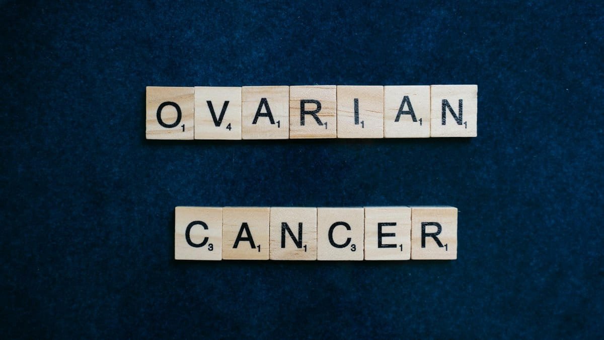 Scrabble tiles spelling 'Ovarian Cancer' on dark background, promoting awareness.