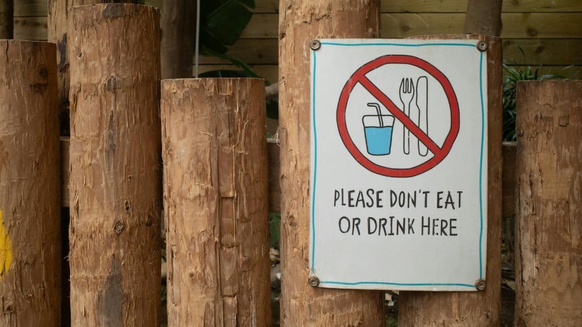 A sign prohibiting eating or drinking attached to wooden logs outdoors.