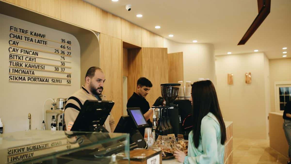 A modern café interior showing baristas preparing coffee and customers at the counter.
