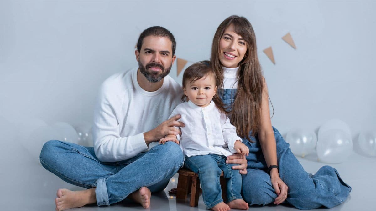A joyful family portrait with parents and child in casual denim, surrounded by balloons.